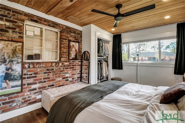 bedroom featuring a closet, wood ceiling, and brick wall