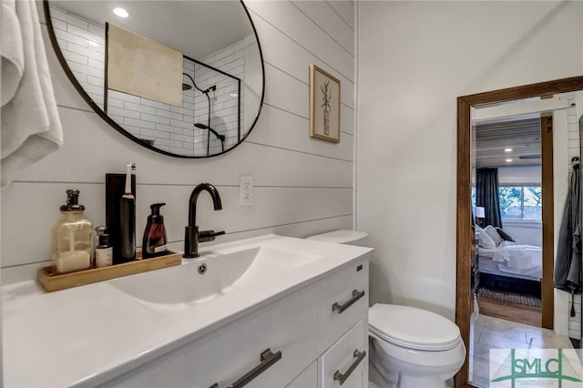 ensuite bathroom with connected bathroom, toilet, vanity, and a tile shower