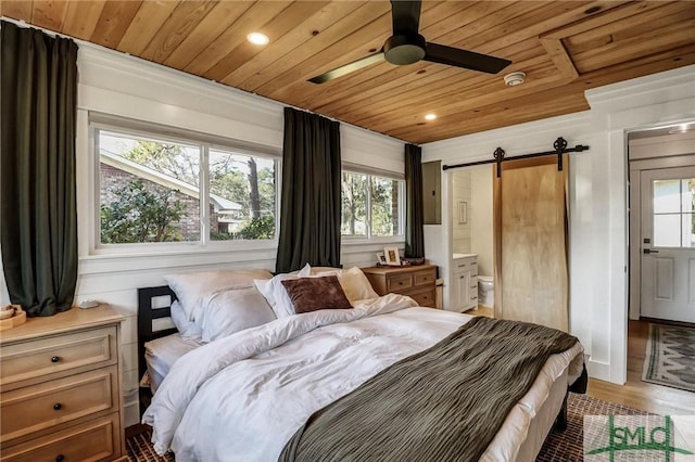 bedroom featuring light wood finished floors, wooden ceiling, ensuite bath, and a barn door