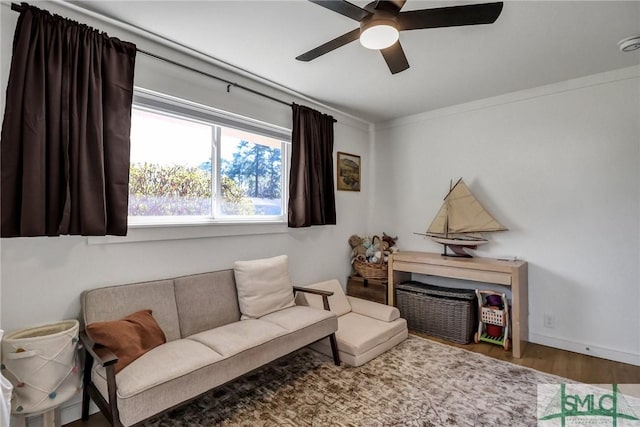 living area with baseboards, wood finished floors, a ceiling fan, and ornamental molding