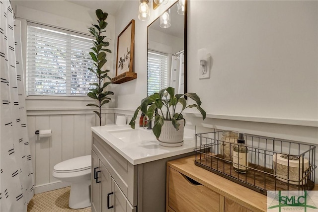 bathroom with vanity, toilet, tile patterned flooring, and wainscoting