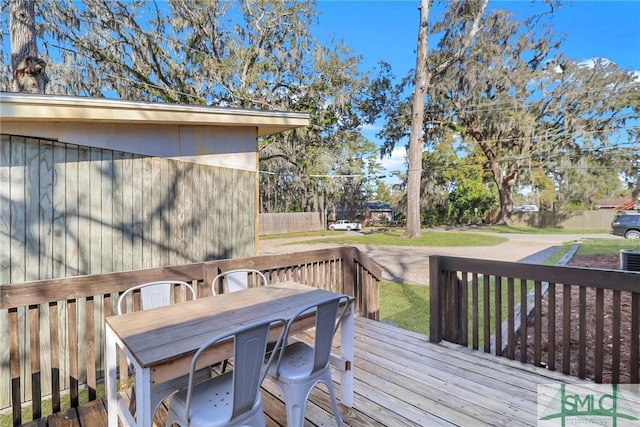 wooden deck featuring outdoor dining space and a lawn