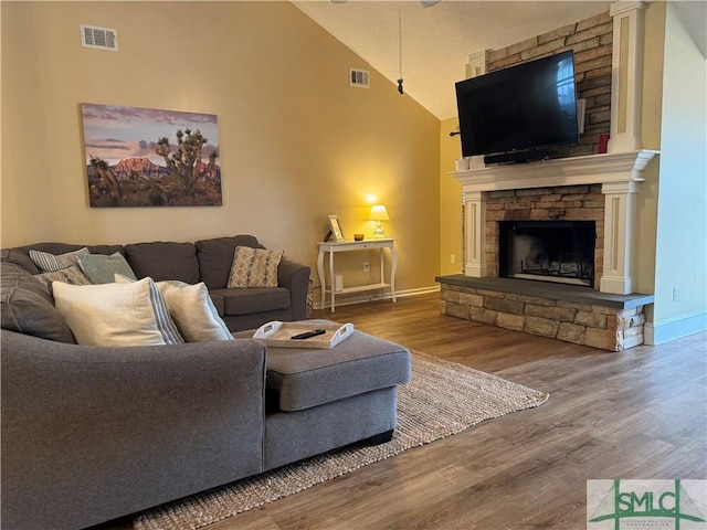 living area featuring wood finished floors, a fireplace, visible vents, and baseboards