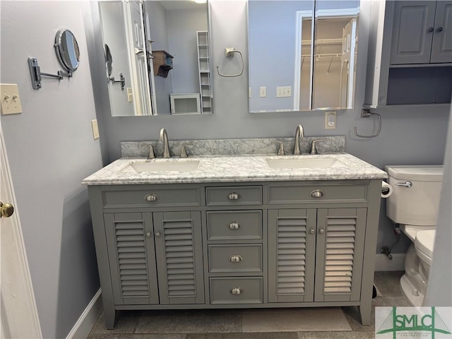 full bath with a sink, baseboards, toilet, and double vanity