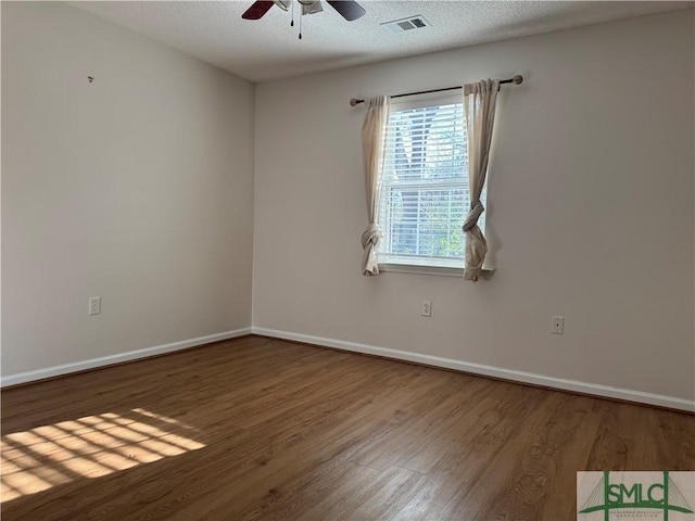 spare room featuring visible vents, a textured ceiling, baseboards, and wood finished floors