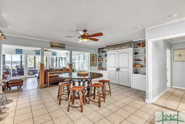 dining space with visible vents, crown molding, ceiling fan, light tile patterned floors, and a textured ceiling