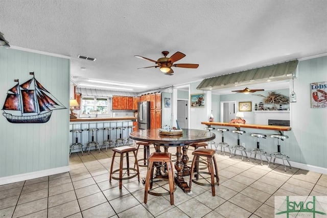 dining space with visible vents, baseboards, ceiling fan, light tile patterned floors, and a textured ceiling