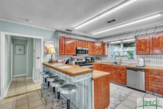 kitchen featuring light tile patterned floors, appliances with stainless steel finishes, a breakfast bar, and a sink