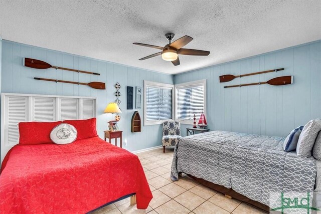 bedroom featuring tile patterned flooring, baseboards, a textured ceiling, and ceiling fan