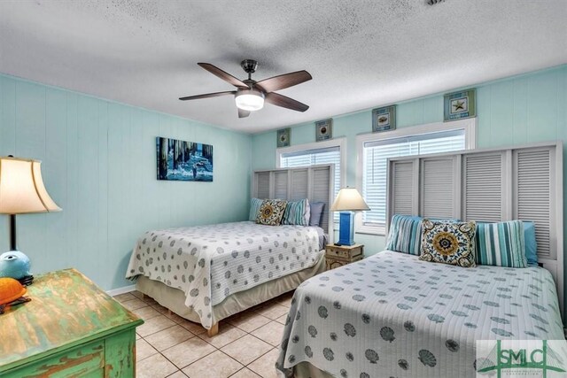 bedroom with ceiling fan, light tile patterned floors, and a textured ceiling