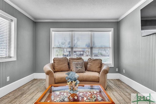 living room featuring crown molding, wood finished floors, baseboards, and a textured ceiling