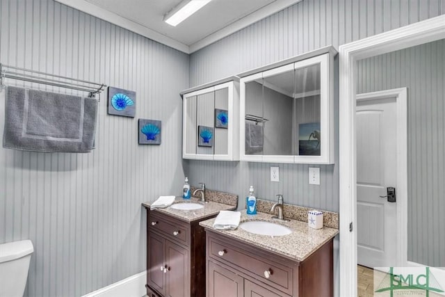 bathroom featuring a sink, toilet, and two vanities