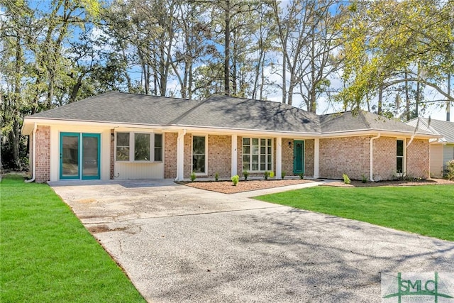 view of front of property with brick siding, concrete driveway, a front yard, and a shingled roof