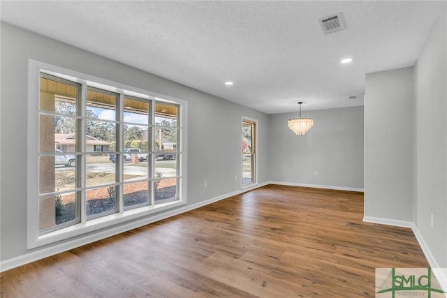 unfurnished dining area featuring a chandelier, baseboards, and wood finished floors