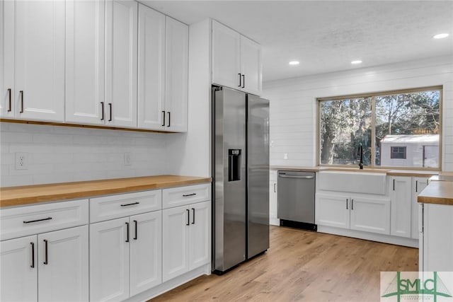 kitchen with light wood finished floors, butcher block countertops, appliances with stainless steel finishes, and a sink