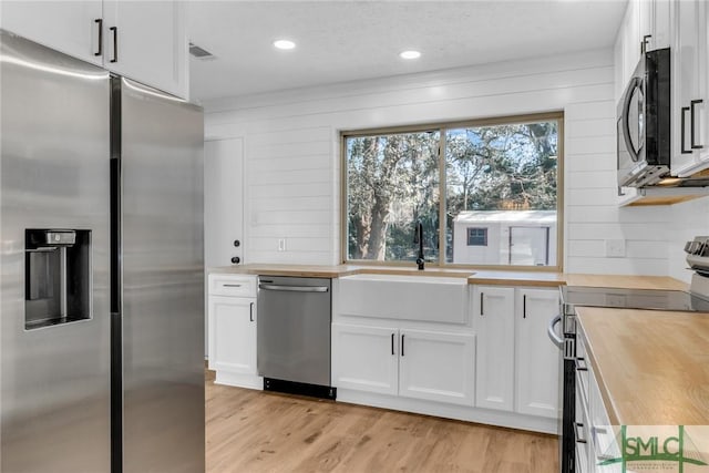 kitchen with butcher block countertops, light wood-style flooring, appliances with stainless steel finishes, and a sink