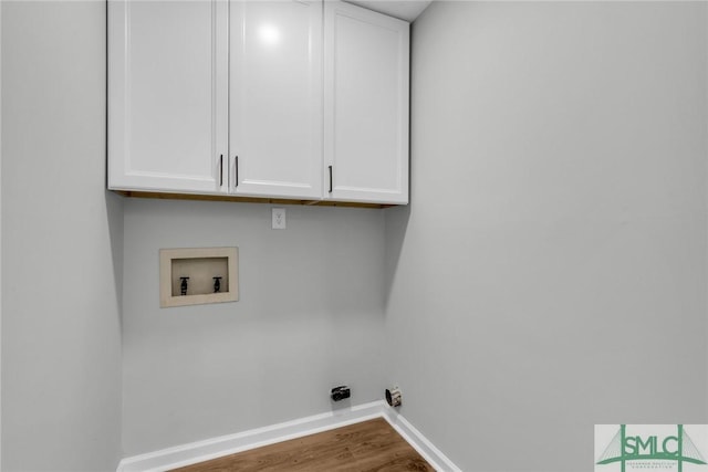 clothes washing area with cabinet space, wood finished floors, baseboards, and washer hookup