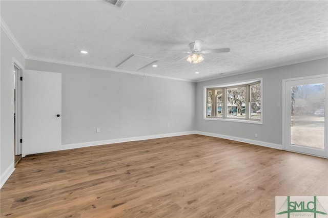 unfurnished room featuring wood finished floors, baseboards, attic access, a textured ceiling, and crown molding