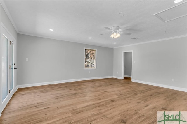 unfurnished room featuring attic access, crown molding, baseboards, and light wood finished floors