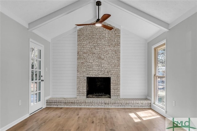 unfurnished living room featuring a brick fireplace, lofted ceiling with beams, ceiling fan, and wood finished floors