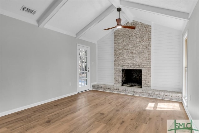 unfurnished living room with wood finished floors, lofted ceiling with beams, a fireplace, and visible vents