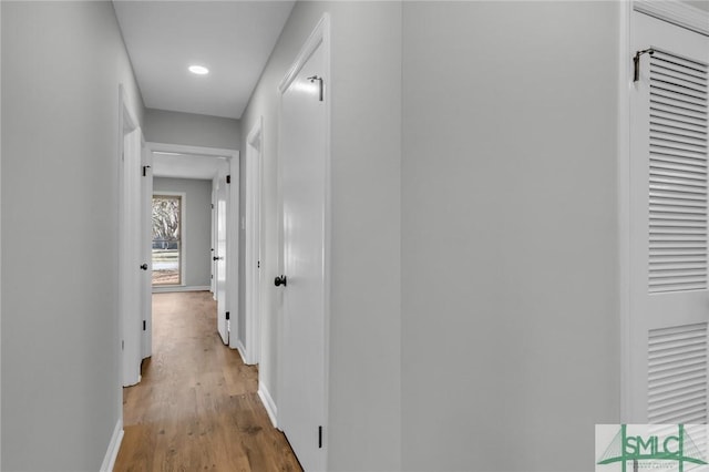 hallway featuring light wood finished floors and baseboards