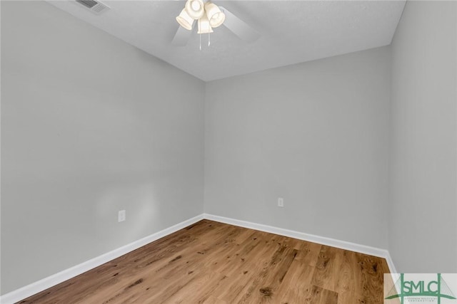 empty room with visible vents, a ceiling fan, baseboards, and wood finished floors