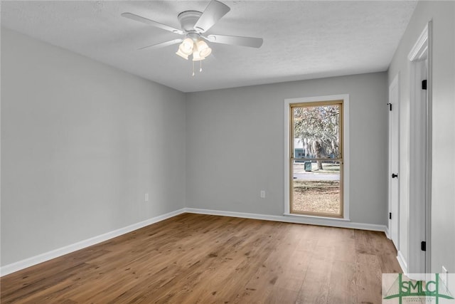 spare room with ceiling fan, a textured ceiling, baseboards, and wood finished floors