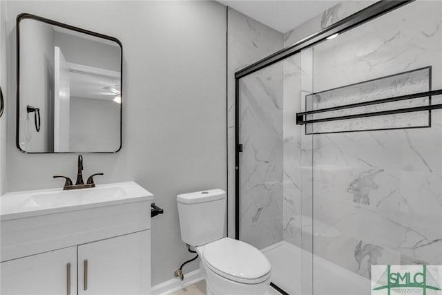 bathroom featuring a marble finish shower, toilet, vanity, and baseboards