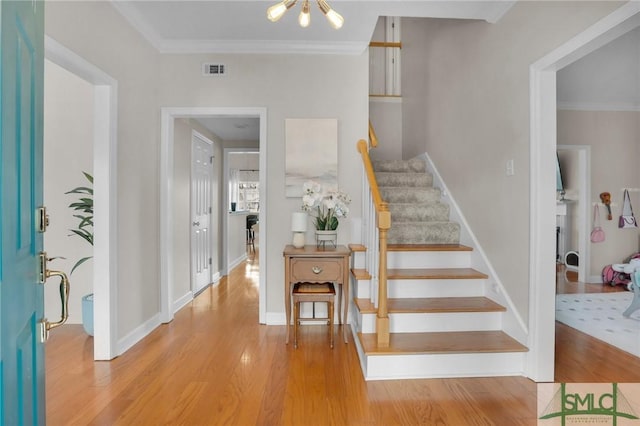 foyer entrance featuring visible vents, wood finished floors, stairway, crown molding, and baseboards