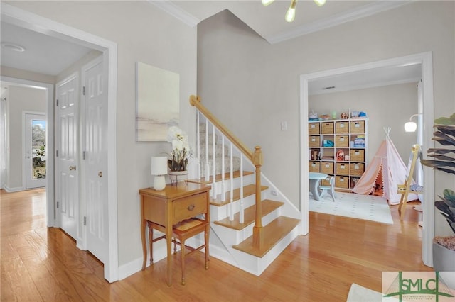 stairway with crown molding, wood finished floors, and baseboards