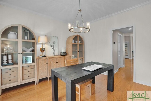 dining room with baseboards, a chandelier, crown molding, and light wood finished floors