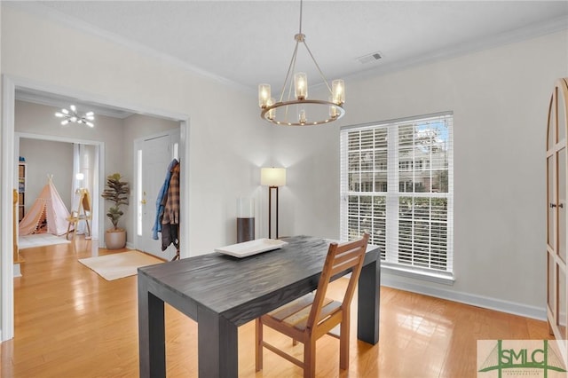 dining area with visible vents, a notable chandelier, light wood-style flooring, and ornamental molding