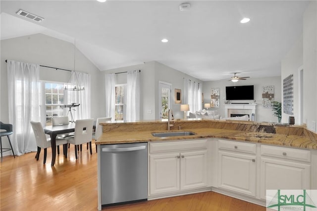 kitchen with visible vents, open floor plan, stainless steel dishwasher, white cabinetry, and a sink