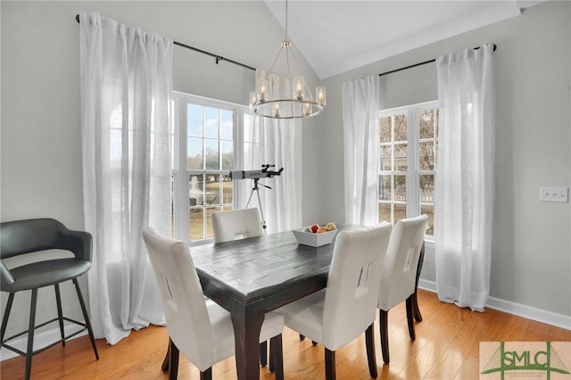 dining room with baseboards, an inviting chandelier, light wood-style flooring, and vaulted ceiling