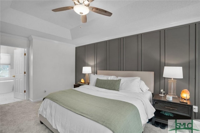 bedroom with crown molding, light colored carpet, a decorative wall, a raised ceiling, and a ceiling fan