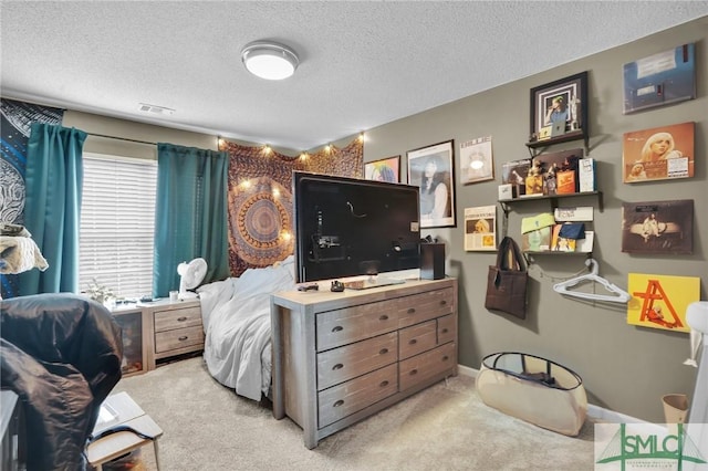 bedroom with carpet, visible vents, and a textured ceiling