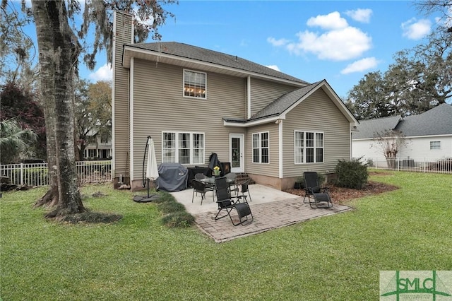 rear view of house with a patio area, a lawn, a chimney, and fence