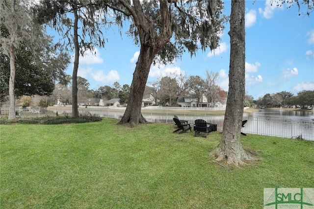 view of yard featuring a water view, an outdoor fire pit, and fence