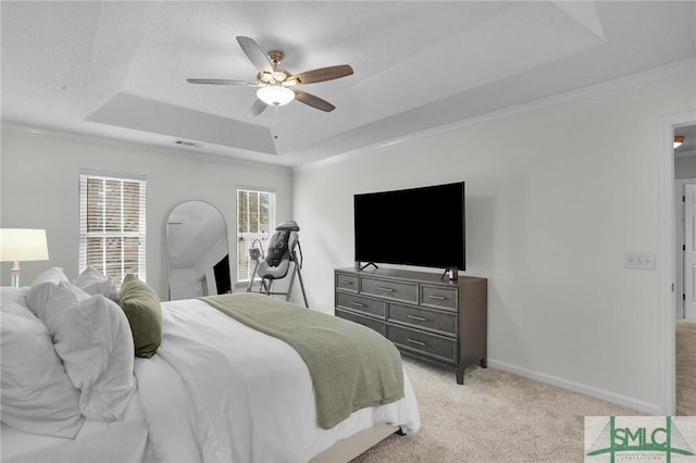 bedroom with a tray ceiling, light colored carpet, baseboards, and visible vents