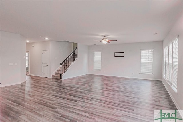 unfurnished living room with stairs, recessed lighting, wood finished floors, and baseboards