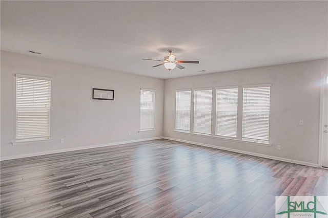 spare room featuring visible vents, baseboards, a ceiling fan, and wood finished floors