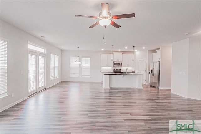 unfurnished living room with recessed lighting, baseboards, light wood-style floors, and a ceiling fan