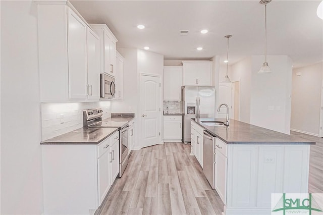 kitchen featuring a sink, dark countertops, light wood-type flooring, and stainless steel appliances