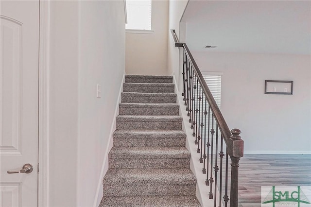 stairway with visible vents, baseboards, and wood finished floors