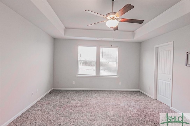 spare room featuring baseboards, a raised ceiling, a ceiling fan, and carpet flooring