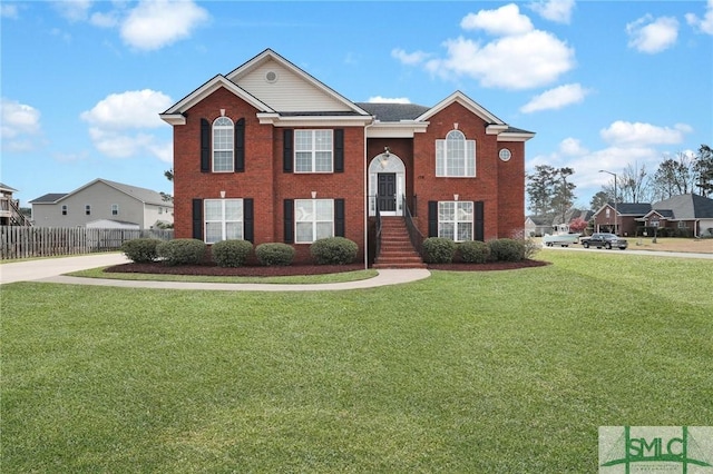 bi-level home with brick siding, a front lawn, and fence