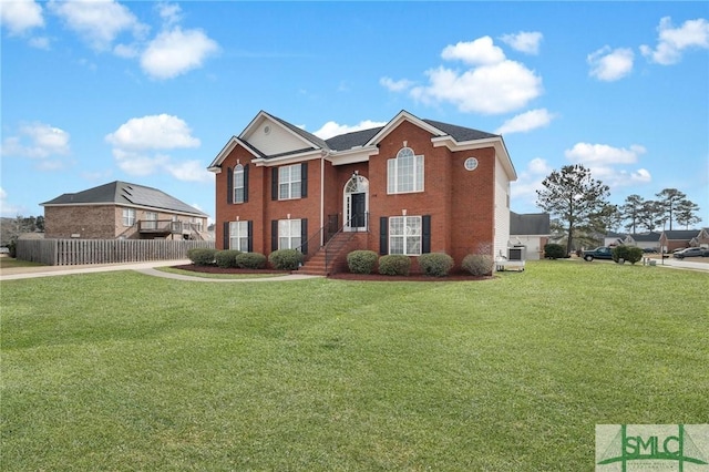 view of front of home with brick siding, a front lawn, and fence