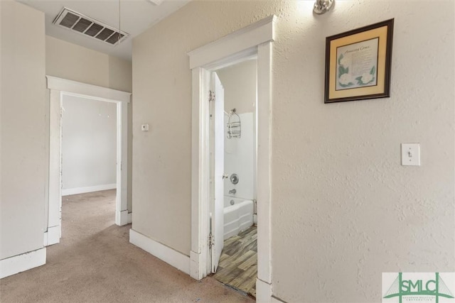 corridor with visible vents, baseboards, a textured wall, and carpet floors