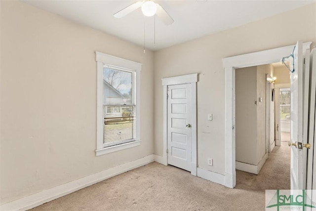 unfurnished bedroom featuring baseboards, light colored carpet, and a ceiling fan